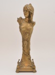 Escultura "Art Noveau" em bronze fundido. Representando busto feminino, erguido por fuste lavradas com penas de pavão. Base recortada e complementada com pequenas figuras de pavão. França. C. 1900. 40 cm.