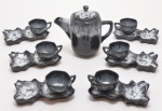 Serviço para café fumoir em porcelana, decoração recoberta em esmaltagem de tonalidade preta, decorado com reações químicas escorridas. Composto por bule e seis xícaras para café, acompanhadas de exóticos pires alongados em cinzeiros. Década de 1960. 16 cm (bule).  5 x 8 cm (xícara) e 16 cm (pires).