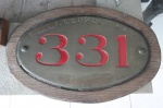 Antiga placa de locomotiva em bronze apresentando inscrição E. F. Leopoldina e numero 331, presa sobre placa em madeira. MI: 31 x 52 cm / 40 x 61 cm.